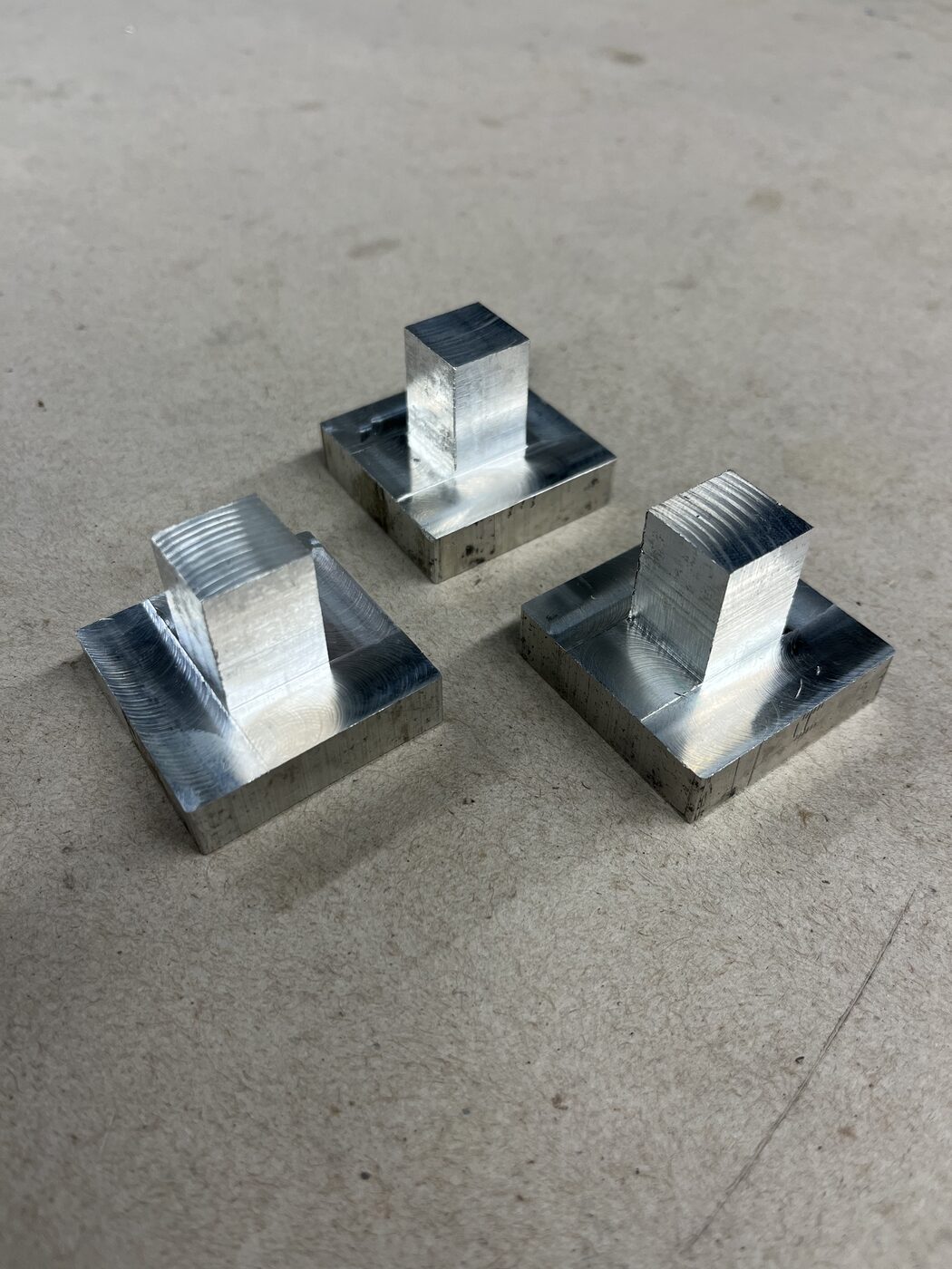 Three finished machined aluminum pivot blocks